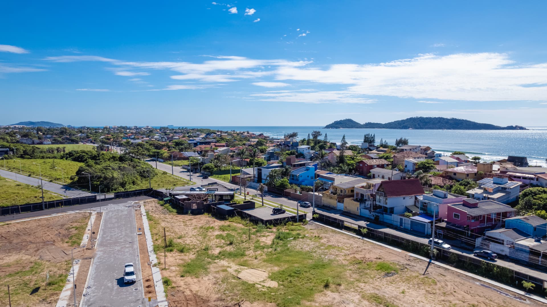 Vista aérea do bairro Campeche em Florianópolis com terreno em preparação, casario baixo, orla e as Ilhas do Campeche ao fundo.